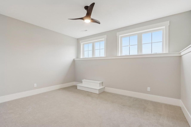 carpeted empty room with visible vents, ceiling fan, and baseboards