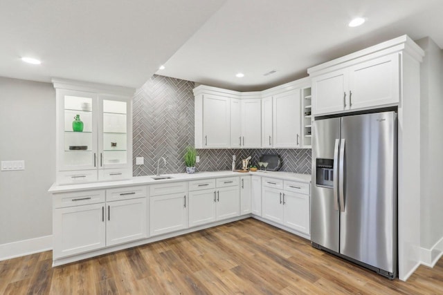 kitchen with light countertops, white cabinets, wood finished floors, and stainless steel refrigerator with ice dispenser