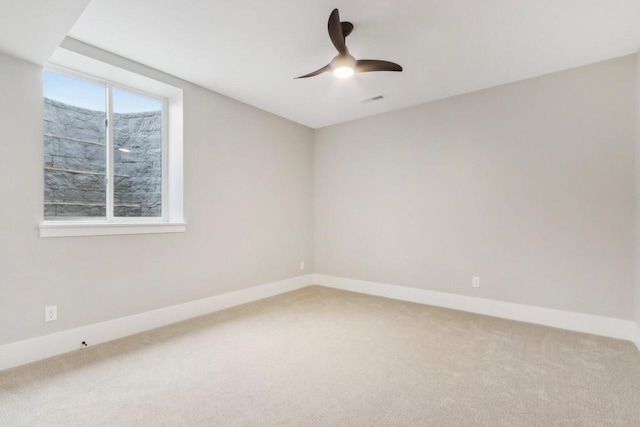 carpeted spare room with visible vents, baseboards, and a ceiling fan