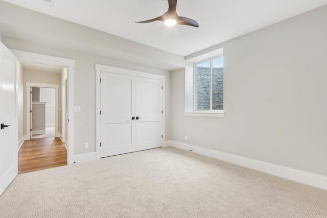 unfurnished bedroom with a ceiling fan, light colored carpet, baseboards, and a closet