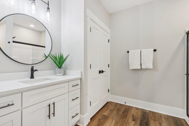 bathroom with vanity, wood finished floors, and baseboards