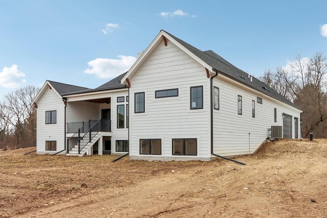 back of house featuring stairs, central air condition unit, and an attached garage