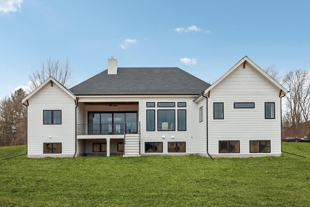 back of house with a lawn, a chimney, a balcony, and a shingled roof