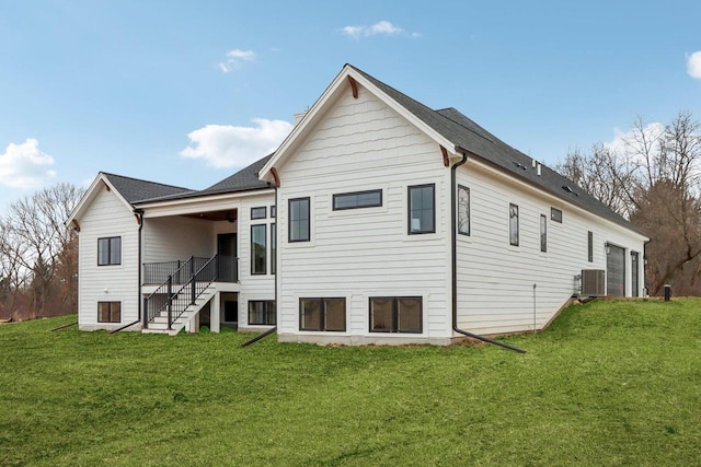 rear view of house with stairs, central AC unit, an attached garage, and a lawn