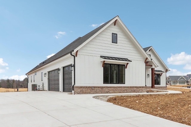 view of front of home featuring brick siding, driveway, a garage, and board and batten siding