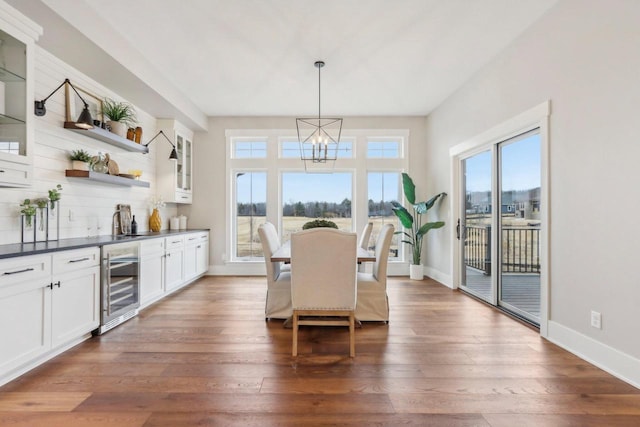 dining room with a chandelier, baseboards, beverage cooler, and dark wood-style flooring