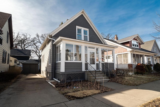 bungalow-style home featuring a storage shed, an outdoor structure, a sunroom, and entry steps