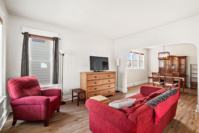 living area featuring arched walkways, baseboards, and wood finished floors