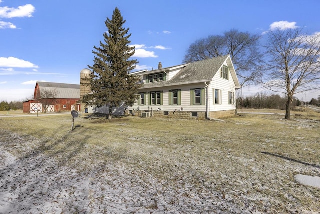 view of front of house featuring an outbuilding, a barn, roof with shingles, and a chimney