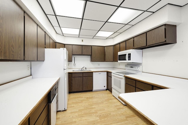 kitchen with white appliances, light wood-style flooring, light countertops, and a sink