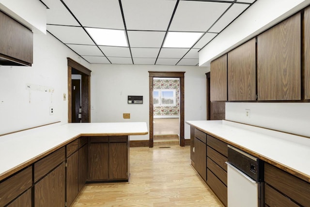 kitchen featuring a drop ceiling, baseboards, light countertops, and light wood-style floors