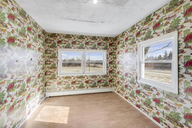 spare room with wallpapered walls, a textured ceiling, and a baseboard radiator