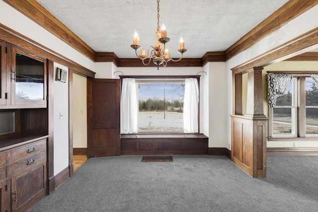 unfurnished dining area featuring an inviting chandelier, carpet, baseboards, and a textured ceiling