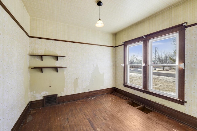 spare room with visible vents, wallpapered walls, and wood-type flooring