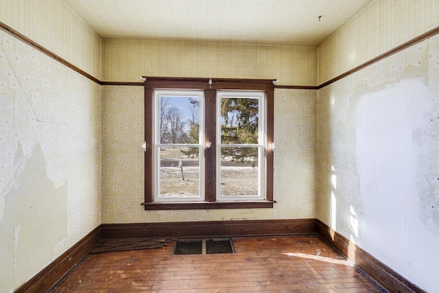 spare room with hardwood / wood-style floors, baseboards, and visible vents