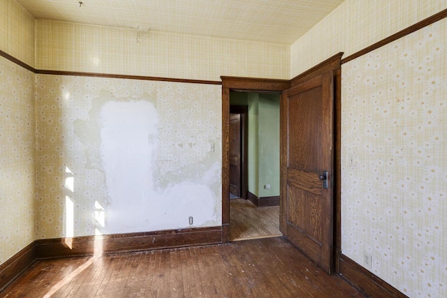 unfurnished room featuring wallpapered walls, baseboards, and dark wood-style flooring