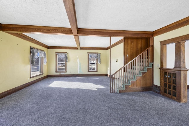 unfurnished living room with beam ceiling, carpet floors, and a textured ceiling