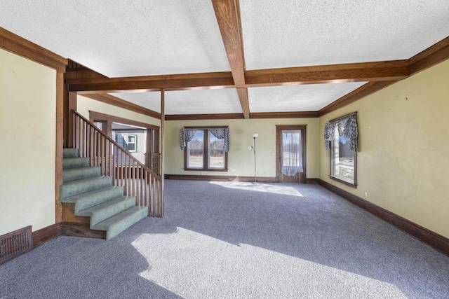 unfurnished living room with visible vents, beam ceiling, a textured ceiling, carpet, and baseboards