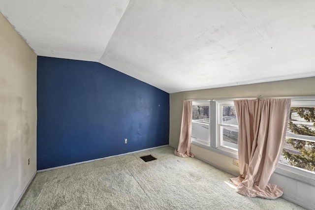 carpeted spare room featuring visible vents and vaulted ceiling