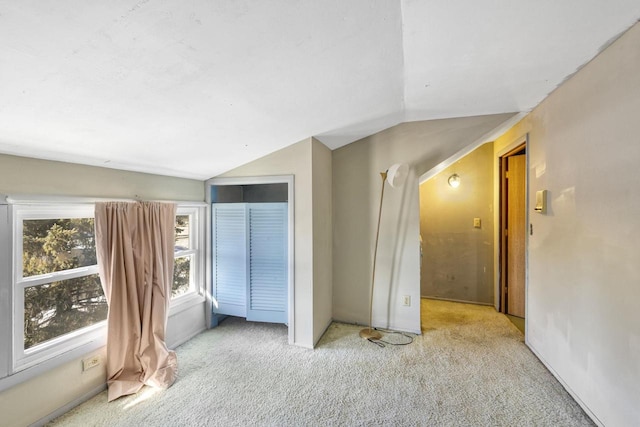 carpeted empty room with vaulted ceiling