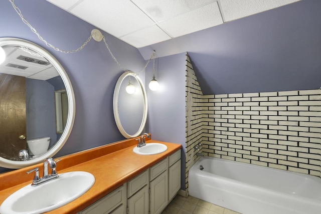 bathroom with tile patterned floors, a bath, a paneled ceiling, and a sink