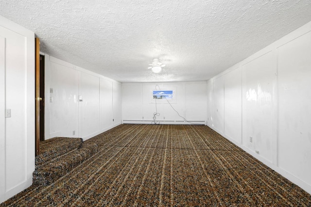 carpeted spare room featuring a baseboard heating unit, a decorative wall, and a textured ceiling