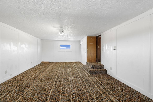 carpeted spare room with stairs, a decorative wall, and a textured ceiling