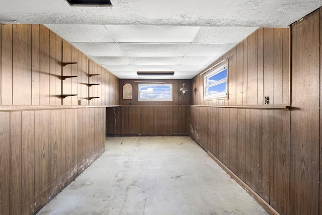 basement with a paneled ceiling and wooden walls