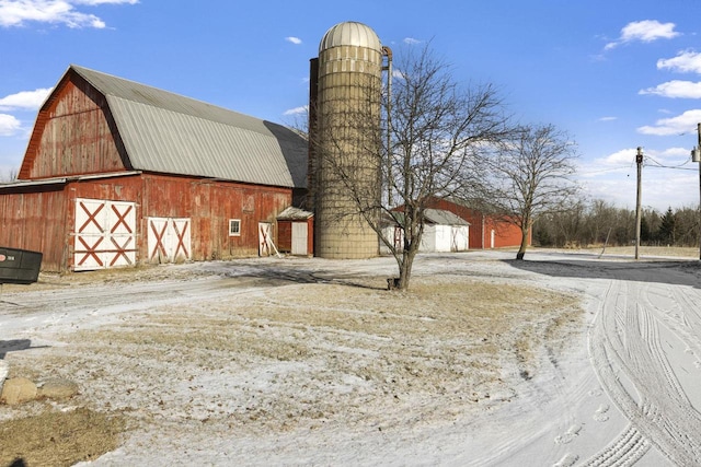 view of property exterior featuring driveway, a gambrel roof, a detached garage, an outdoor structure, and a barn