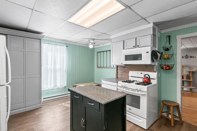 kitchen featuring white appliances, a kitchen island, light wood-style flooring, ceiling fan, and baseboard heating