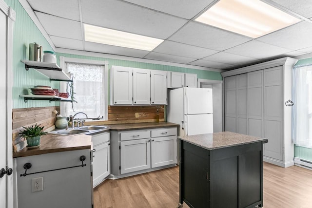 kitchen featuring open shelves, a paneled ceiling, freestanding refrigerator, and a sink