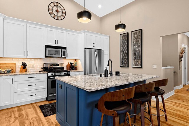 kitchen featuring a kitchen bar, a sink, tasteful backsplash, appliances with stainless steel finishes, and light wood finished floors