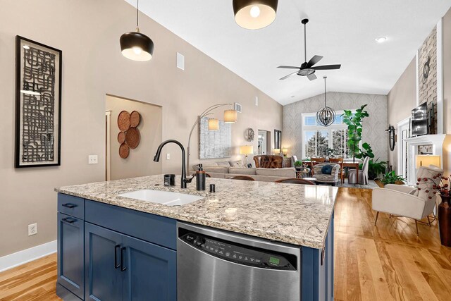 kitchen featuring blue cabinetry, open floor plan, dishwasher, light wood-style floors, and a sink