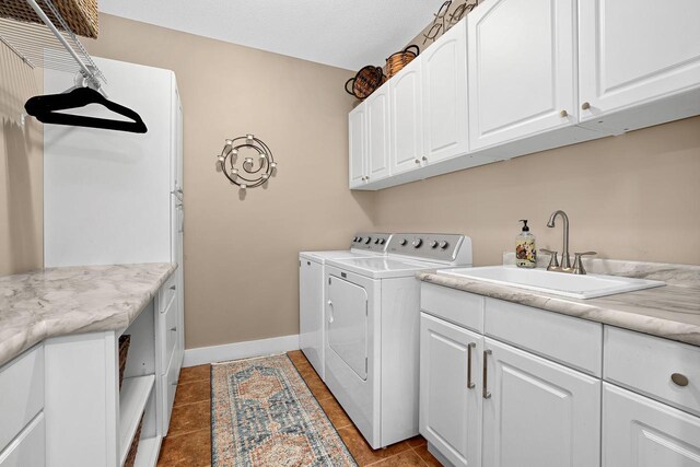 laundry area featuring baseboards, washing machine and dryer, light tile patterned floors, cabinet space, and a sink