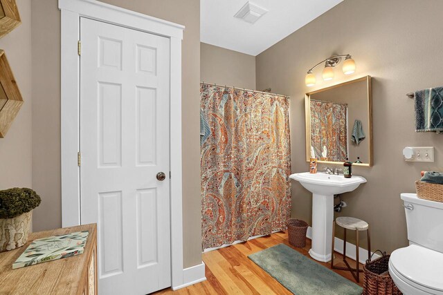 full bath with visible vents, toilet, wood finished floors, a shower with shower curtain, and baseboards