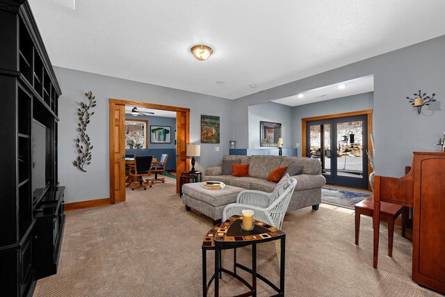 living room with french doors, baseboards, light colored carpet, and a textured ceiling