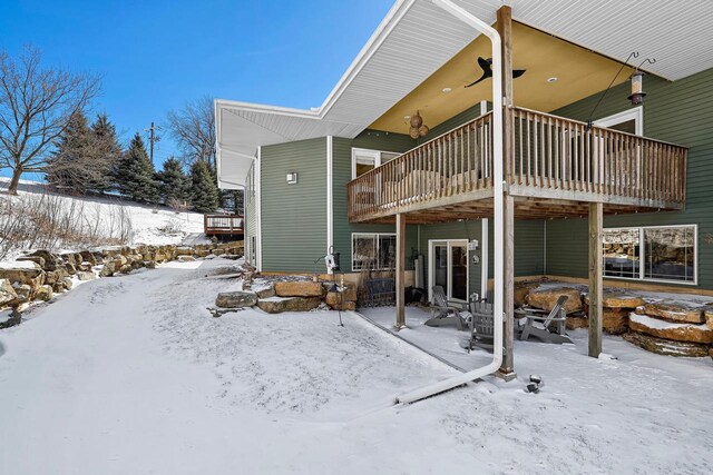 snow covered back of property with a patio area