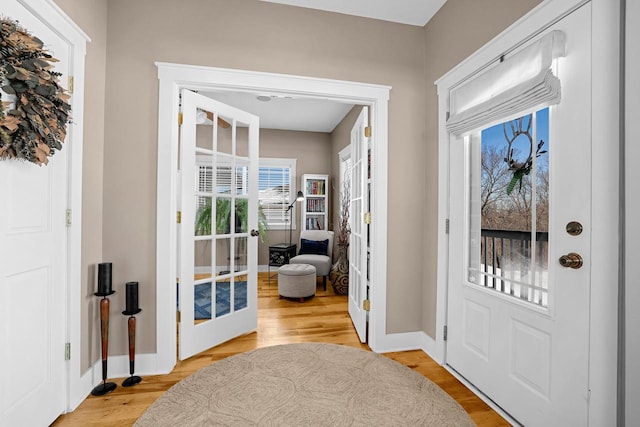 doorway to outside featuring light wood-style floors, baseboards, and french doors