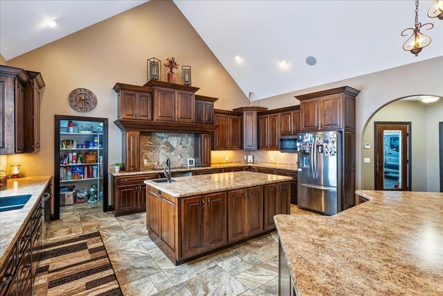 9073 Richfield Dr, Marshfield, WI 54449 - kitchen with stainless steel fridge with ice dispenser, dark brown cabinetry, hanging light fixtures, arched walkways, and a kitchen island with sink