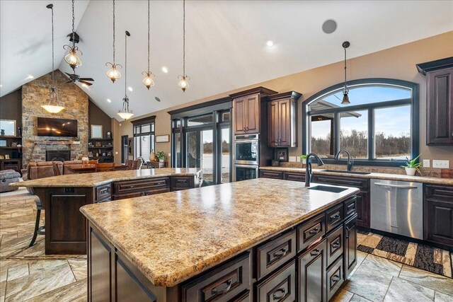 9073 Richfield Dr, Marshfield, WI 54449 - kitchen with a healthy amount of sunlight, a fireplace, stainless steel appliances, and a kitchen island with sink