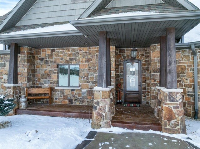 9073 Richfield Dr, Marshfield, WI 54449 - snow covered property entrance featuring stone siding and a porch