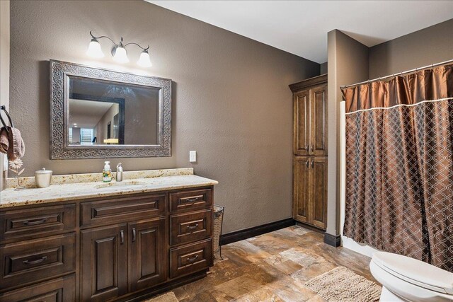 9073 Richfield Dr, Marshfield, WI 54449 - bathroom with vanity, a shower with curtain, baseboards, stone finish flooring, and toilet