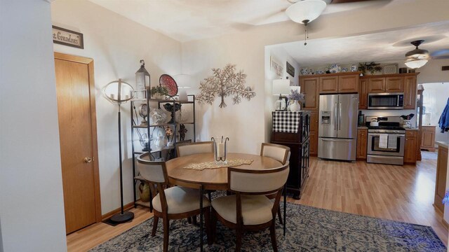 dining area with baseboards, a ceiling fan, and light wood finished floors