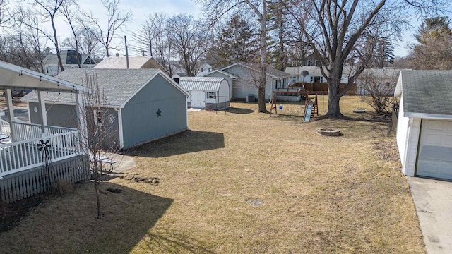 view of yard with a storage shed, an outbuilding, a fire pit, and a residential view