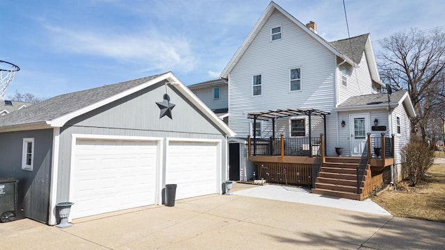 view of front of house featuring a deck, a pergola, roof with shingles, an outdoor structure, and a chimney