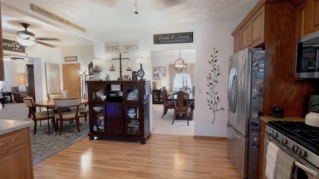 kitchen featuring a ceiling fan, light wood-style floors, brown cabinets, and appliances with stainless steel finishes