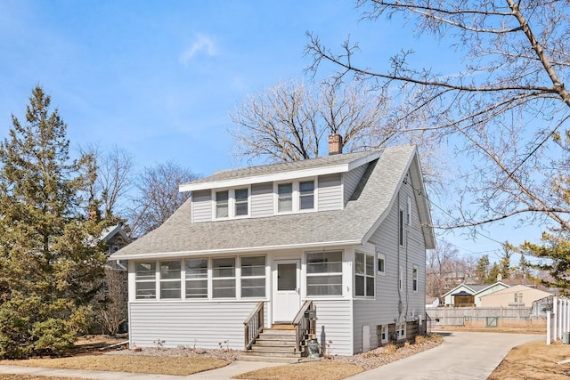 bungalow with entry steps, fence, a chimney, and a shingled roof