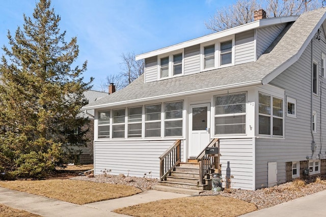 view of front of house with a shingled roof, entry steps, and a chimney