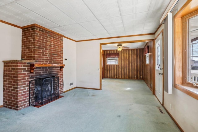 unfurnished living room with crown molding, carpet flooring, a fireplace, and visible vents