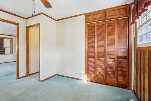 unfurnished bedroom featuring light carpet, baseboards, crown molding, and a closet